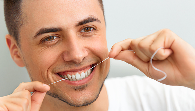 A man enjoying his favorite type of floss that his Marietta, OH dentist recommended to him.