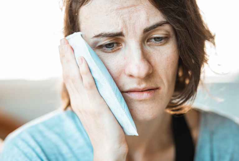 woman holding ice pack on painful mouth