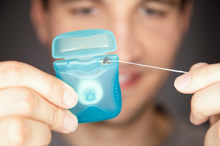 Male pulling floss out of box ready to use and get stucked food out of teeth