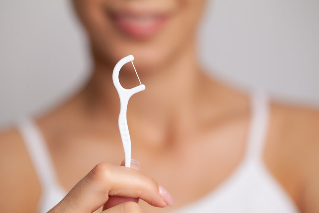 Portrait of beautiful woman cleaning teeth with dental floss.